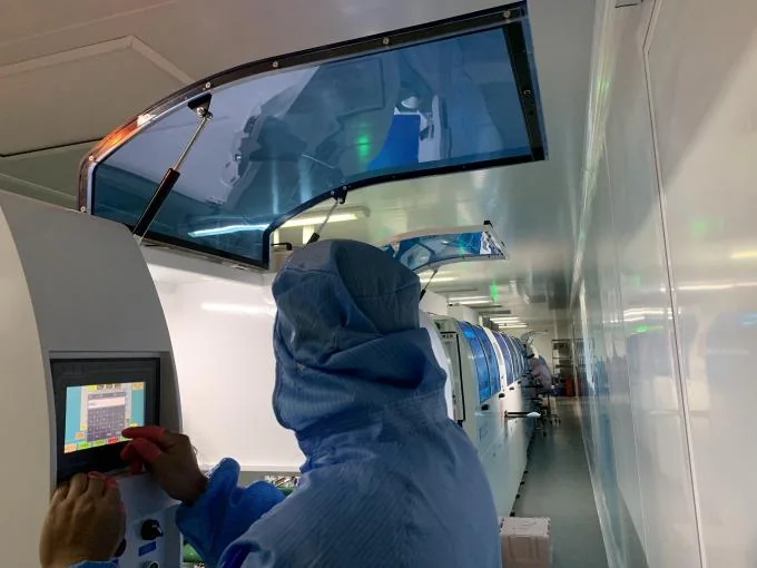Operator in a full coverall at a clean-booth machine terminal
